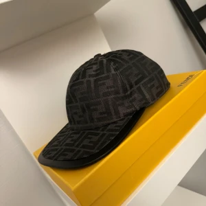 Svart Fendi keps med FF-mönster - Snygg svart keps från Fendi med det klassiska FF-logomönstret över hela kepsen. Kepsen har böjd skärm och justerbar rem baktill. Materialet är slitstark bomull med en lyxig känsla. Perfekt för dig som vill ha en exklusiv streetstyle-look.