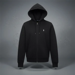 Polo Ralph Lauren zip hoodie - Mörkblå hoodie från Polo Ralph Lauren med klassisk vit logga på bröstet. Tröjan har huva med snörning, dragkedja framtill och två fickor. Tillverkad i mjuk bomullsmix som är skön att ha på sig. Perfekt för chill dagar och streetwear-stil.