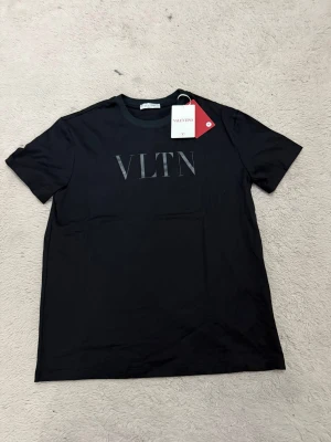 Svart VLTN t-shirt från Valentino - Svart t-shirt från Valentino med VLTN-logga tryckt framtill. Klassisk rund hals och korta ärmar. T-shirten har en stilren, enkel design som passar perfekt till jeans eller shorts. Snygg och modern look med exklusiv känsla. 