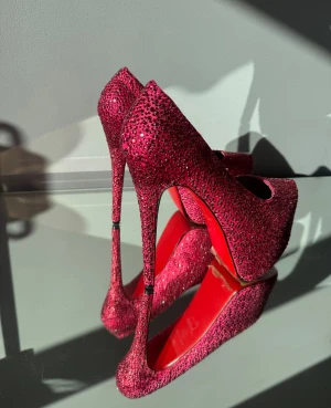 Höga platå Klackskor Rosa, Strl 39 - Säljer nu mina fantastiska rosa klackskor likande Louboutins. Täckta med gnistrande rhinestones och har den ikoniska röda sulan. Dem är knappt använda har mer haft skorna som en fin prydnad på skohyllan  -Storlek 39 -Klackhöjd 16 cm  -Platå 7 cm