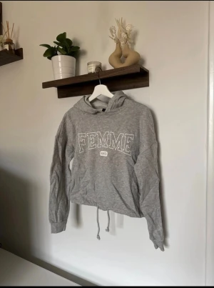 Grå hoodie från Gina Tricot - Grå croppad hoodie från Gina Tricot med knytning i midjan. Storlek XS Tillverkad i mjuk bomullsblandning av bomull och viskos.