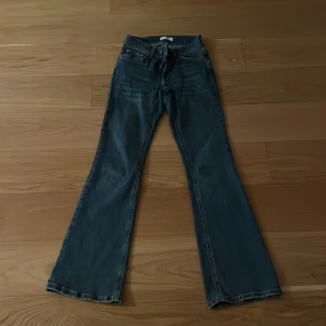 Blå bootcut jeans från Gina Tricot - Snygga blå jeans från Gina Tricot i klassisk bootcut-modell. Jeansen har fyra fickor, normal passform och är tillverkade i ett slitstarkt denimtyg. Perfekta för dig som gillar en retroinspirerad look med utsvängda ben.