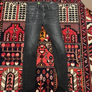 Diesel D-Amny svarta slim fit jeans  - Svarta slim fit jeans från Diesel, modell D-Amny. Snyggt tvättade med diskreta slitningar och klassiska fem fickor. Stretchigt denim-material som sitter tajt hela vägen ner. Perfekt för dig som gillar riktigt bra slim fit jeans.