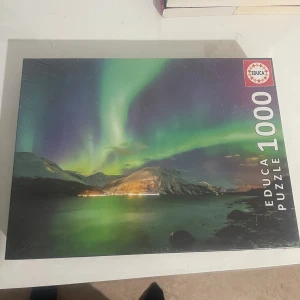 Educa Puzzle 1000 - Upplev magin av norrsken med detta 1000-bitars pussel! Perfekt för dig som gillar utmaningar och vackra naturmotiv. Samla vänner eller koppla av själv medan du pusslar ihop ett spektakulärt landskap under stjärnhimlen.