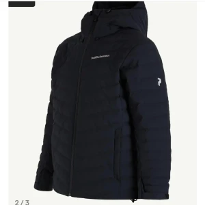 Svart Peak Performance Jacka  - Peak Performance dunjacka i svart med huva och diskret logga på bröstet och ärmen. Jackan är regntålit. Är bara använd en säsong. Ny priset för jacken är 4 000kr
