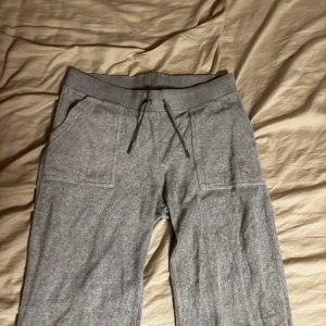 Grå Juciybyxor!! - Grå Juciybyxor i bomullsmix med snörning i midjan och stora fickor fram. Bakfickor med lock och knappar samt broderad detalj på ena benet. Perfekta för chill dagar eller när du vill vara extra bekväm. Köpta från Nelly, använda max 3 gånger!! Ligger och tar onödig plats i gaderoben!