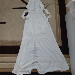 Vit långklänning från Misscix - Supersnygg vit långklänning från Misscix med omlott och knyt i ryggen. Klänningen har smock i midjan, broderade detaljer framtill och är ärmlös. Materialet är mjukt och lätt, perfekt för varma dagar. Stilren och fräsch look som verkligen sticker ut.