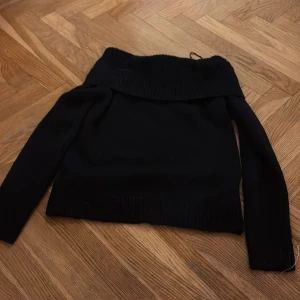 Svart polotröja från Gina Tricot - Svart polotröja från Gina Tricot med bred ribbad krage som kan vikas ner. Tröjan har långärmad design och är stickad i mjukt material, perfekt för kyliga dagar. Enkel och stilren modell som funkar till många olika looks.