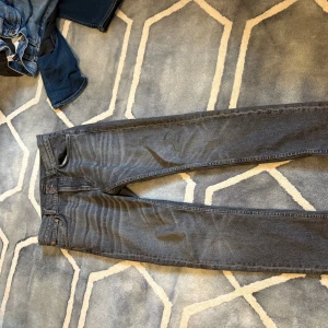 Grå jeans från Nudie Jeans, W29 L32 - Snygga grå jeans från Nudie Jeans med klassisk femficksdesign och subtila slitningar. Modellen har rak passform och normal midja, perfekt för dig som gillar stilrena och tidlösa jeans. Materialet är mjukt och slitstarkt denim. Ord pros 1800, lean Dean 