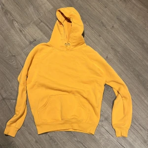 Gul hoodie från Bik Bok XS - Säljer en gul hoodie från Bik Bok i storlek XS. Tröjan har en klassisk huva med snörhål, stor magficka och ribbade muddar vid ärmslut och nederkant. Perfekt för dig som gillar färgstarka och bekväma plagg.