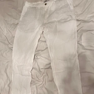 Vita linnebyxor från Dressmann - Snygga vita linnebyxor från Dressmann med klassisk passform. Byxorna har framfickor, bakfickor med knapp och stängs med en knapp framtill. Perfekta för varma dagar när du vill ha en luftig och stilren look.