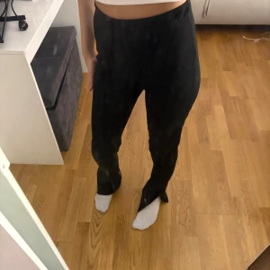 Svarta byxor med slits - Byxor med slits och högmidja. Aldrig använts och så gott som ny. Väldigt stretchiga och därför passar storlek Xs, S och M