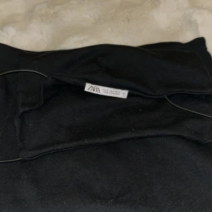 Svart långklänning från Zara - Svart långklänning från Zara med smala axelband och rak siluett. Enkel och stilren design som ger en snygg look. Materialet är mjukt och följsamt, perfekt för dig som gillar minimalistisk stil.