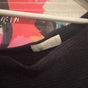 Svart ribbad topp från LeGer - Säljer en svart ribbad topp från LeGer med bred halsringning och trekvartsärm. Toppen har en tight passform och är tillverkad i ett mjukt stickat material som sitter snyggt på kroppen. Perfekt för dig som gillar stilrena och enkla plagg.