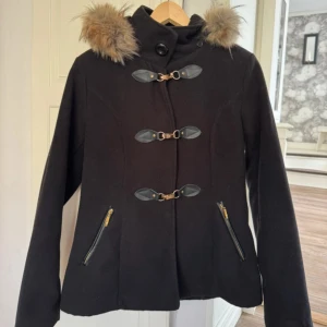 Svart kappa  - Säljer min svarta kappa från Italien, märke okänt. Har avtagningsbar fuskpäls. Finns inte någon lapp med storlek med sitter som en storlek Small.