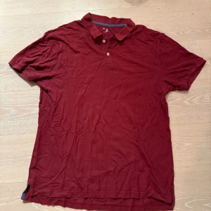 Vinröd pikétröja från Gap XXL - Snygg vinröd pikétröja från Gap i storlek XXL. Klassisk krage och två knappar framtill. Tillverkad i mjuk bomull som är skön mot huden. Perfekt för dig som gillar enkel och stilren design med en djup röd färg.