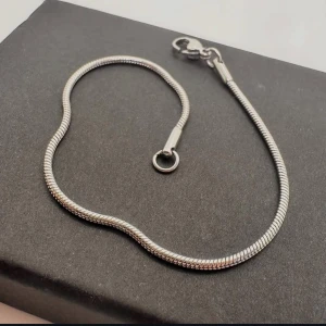 Silvrigt ormlänksarmband - Stilrent silvrigt armband med ormlänksdesign och smidig karbinlås. Perfekt för dig som gillar minimalistiska och moderna smycken. Passar både ensam eller i kombination med andra armband för en personlig look.