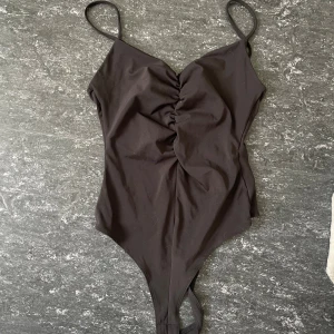 Svart body med rynk framtill - Snygg svart body med smala axelband och rynkade detaljer framtill. 