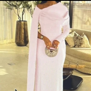 Ljusrosa långklänning med oneshoulder - Säljer en elegant ljusrosa balklänning med oneshoulder-design och lång ärm på ena sidan. Klänningen har en stilren och modern siluett som ger en sofistikerad vibe. Perfekt för dig som vill sticka ut med en unik look.