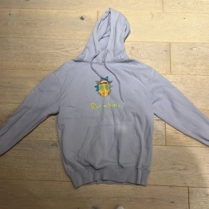 Rick and Morty hoodie från Pull&Bear XS - Ljuslila Rick and Morty hoodie från Pull&Bear i storlek XS. Stor färgglad print både fram och bak med coolt motiv och logga. Klassisk känguruficka, snörning i huvan och mjukt bomullsmaterial. Perfekt för dig som älskar serien och vill sticka ut.