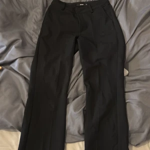 Svarta kostymbyxor från BikBok - Svarta kostymbyxor från BikBok med lite utsvävning nertill, i modellen vilma, lite slitna där bak annars jätte fina!