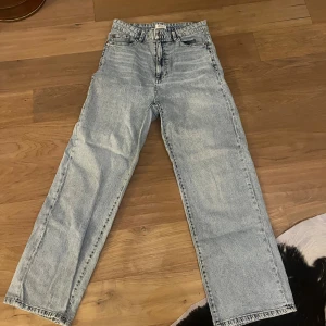 ljusa jeans  - Säljer ett par klassiska jeans i ljusblå tvätt med rak passform och hög midja. Jeansen har knappgylf och är tillverkade i slitstarkt bomullsjeans. Perfekta för dig som gillar vintagevibe och tidlös stil.