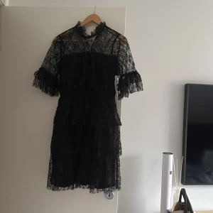 Svart spetsklänning från Bubbleroom - Smilla Lace Dress från Bubbleroom i svart spets med volanger. Klänningen har kort längd och trekvarts ärmar. Nypris 699kr