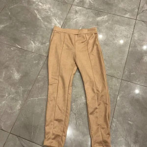 Beiga mocka byxor  - Säljer ett par beiga byxor från SHEIN i storlek L. De har en lagom hög midja och har ett mjukt mocka material på utsidan .Snygg söm framtill ger en extra detalj. Byxorna är helt nya! 