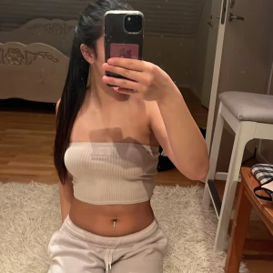 Beige ribbad tubtopp från H&M Divided - Säljer en beige ribbad tubtopp från H&M Divided. Toppen är bandeau-modell, ärmlös och har en tight passform. Perfekt att styla med jeans eller kjol för en clean look. Mjuk och stretchig i materialet, superenkel att matcha med allt.