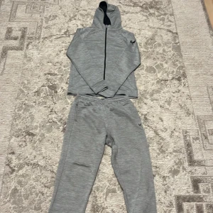 Grå hoodie från SOC med dragkedja - Snygg grå hoodie från SOC med hel dragkedja och huva. Tröjan har långa ärmar och svart logga på ärmen. tillverkad i mjukt syntetmaterial som andas. Matchar enkelt med andra plagg och har en sportig vibe.