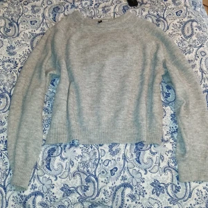 Ljusgrå stickad tröja från Divided - Supermysig ljusgrå stickad tröja från Divided i storlek L men passar mig perfekt som har m/s. Tröjan har en klassisk rund halsringning, ribbade muddar och är långärmad. Perfekt att slänga på sig när det är kyligt ute och funkar till allt från jeans till kjol. Köptes för 250