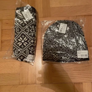 Marinblå mönstrade merinoullvantar Cervinia - Säljer ett par marinblå vantar från Cervinia i mjuk merinoull. Vantarna har ett klassiskt nordiskt mönster i vitt och marinblått, perfekt för kalla dagar. Snygg och tidlös design som sticker ut med sitt stickade mönster.