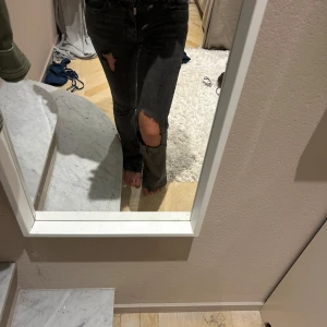 Svarta bootcut jeans med slitningar - Säljer ett par svarta jeans med bootcut-modell och snygga slitningar på låret och knät. Jeansen har medel midja De heter lossnat bootcut på gina. Jag är 163 på bilden