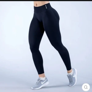 Svarta leggings från DFYNE - Snygga svarta leggings från DFYNE med hög midja och tight passform. Perfekta för träning eller chill, tillverkade i stretchigt syntetmaterial som sitter skönt och formar kroppen. Diskret logga vid linningen för en clean look. Impact leggings.