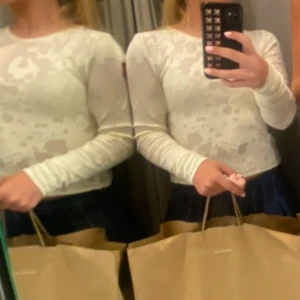 Vit långärmad mesh-topp - Säljer en vit långärmad mesh-topp med abstrakt mönster. Toppen är tight och har en croppad passform som ger en trendig look. Perfekt att styla med kjol eller jeans för en cool outfit.