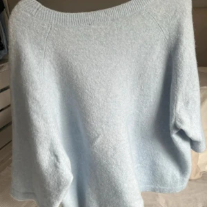 Ljusblå stickad tröja & Other Stories - Supermjuk och oversized ljusblå stickad tröja från & Other Stories. Tröjan har rund halsringning och korta ärmar, perfekt för lager-på-lager. Enkel och stilren design som är lätt att matcha med jeans eller kjol.