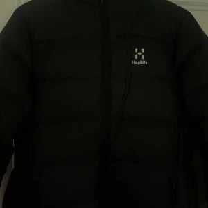 Svart dunjacka från Haglöfs dam M - Svart dunjacka från Haglöfs i dammodell, storlek M. Vatten och vindtålig. 