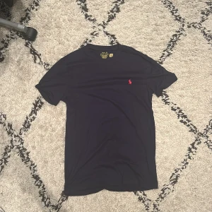 Svart t-shirt Polo Ralph Lauren S - Svart t-shirt från Polo Ralph Lauren i bomull med klassisk röd broderad logga på bröstet. Modellen är slim fit och har rund hals och korta ärmar. Perfekt basic med snygg passform och stilren look. Storleken sitter mellan XS - S. Aldrig använd endast testad 