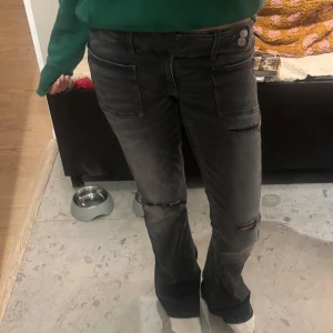 Gråa bootcut gina young jeans - Säljer ett par svarta jeans med slitningar på knäna och stora framfickor. Jeansen är bootcut och  låg midja. Använd fåtal gånger, superbra skick!! Storlek 170❣️