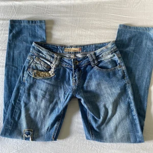 Blå jeans från Fishbone med slitningar - Blå jeans från Fishbone med slitningar och detaljer vid fickorna, strl 27.