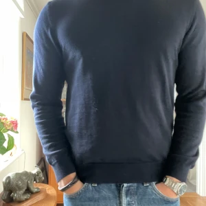 Mörkblå merinoulltröja från Sand - Snygg mörkblå stickad tröja från Sand Copenhagen i 100% merinoull. Klassisk rund halsringning och långärmad modell med normal passform. Perfekt för dig som gillar stilrena och tidlösa plagg med premiumkänsla. Pris kan diskuteras vid köp av flera varor