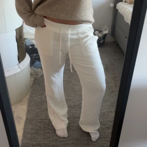 Vita linnebyxor med snörning - Snygga vita linnebyxor med raka ben och bred resår i midjan. Byxorna har snörning framtill och stora fickor på sidorna. Perfekta för en avslappnad och chill stil.