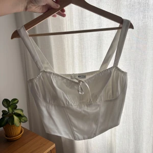 Vit satin korsettopp från NA-KD - Supersnygg vit korsettopp från NA-KD i glansigt satinmaterial. Storlek S använd en gång 