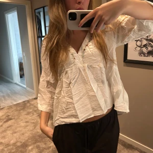 Vit blus  - Superfin vit blus från Zara med v-ringning och små färgglada pärlor längs ringningen. Blusen har en lös passform, trekvartsärmar och är gjord i ett lätt, skrynkligt bomullstyg. Passar S/M