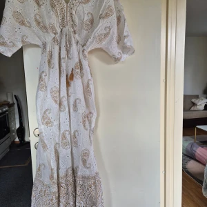 Vit långklänning med paisleymönster - Superfin cit klänning. I helt ny skick utan prislapp. Skriv vid minsta fundering och priset går att diskutera.