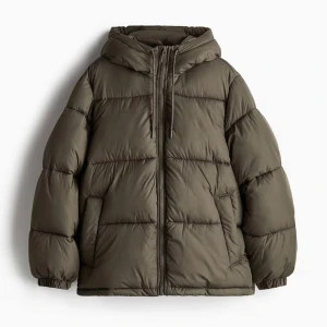 Olivgrön pufferjacka med huva - Säljer en olivgrön pufferjacka med huva och dragsko. Jackan har en oversized passform, dragkedja framtill och elastiska muddar vid ärmsluten. Perfekt för kalla dagar och riktigt skön att bära. Materialet är syntet och jackan är quiltad för extra värme.