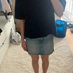 Blå jeanskjol från Weekday, strl 34 - Säljer en klassisk blå jeanskjol från Weekday i modell Wend Skirt. Kjolen är kort med rå, fransig fåll och har femficksdesign samt knapp- och dragkedjestängning framtill. Perfekt för dig som gillar en avslappnad och trendig stil.