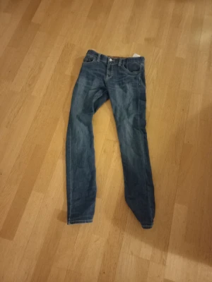Levi's 511 blå jeans pojke sz 158 - Säljer ett par klassiska Levi's 511 jeans i blå tvätt. Modellen är slim med raka ben och normal midja. Jeansen har fem fickor, Levi's ikoniska röda lapp och patch bak i midjan. Perfekta till sneakers och hoodie för en chill look.