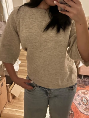 Stickad tröja - Mysig beige stickad tröja från Gina Tricot i storlek S. Tröjan har trekvartsärmar och en enkel, avslappnad passform. Perfekt till jeans och funkar året runt för en chill look.