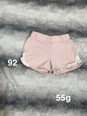 Lindex shorts - Säljer ett par ljusrosa shorts med elastisk midja och vita spetsdetaljer på sidorna. perfekta för varma dagar.🌸 Fint använt skick. Storlek 92